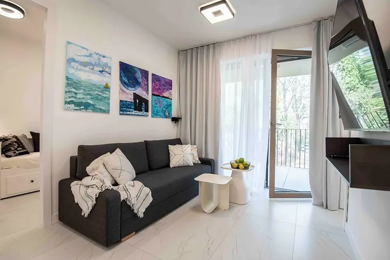 Obývák se sedačkou, obrazy moře a vstupem na balkon